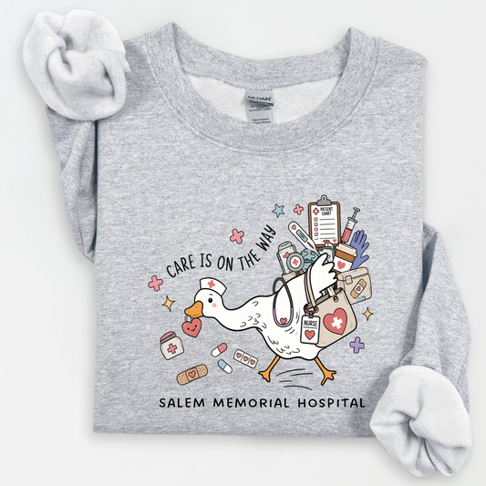 Care Is on the Way nurse goose design with Salem Memorial Hospital lettering on a sport grey crewneck sweatshirt